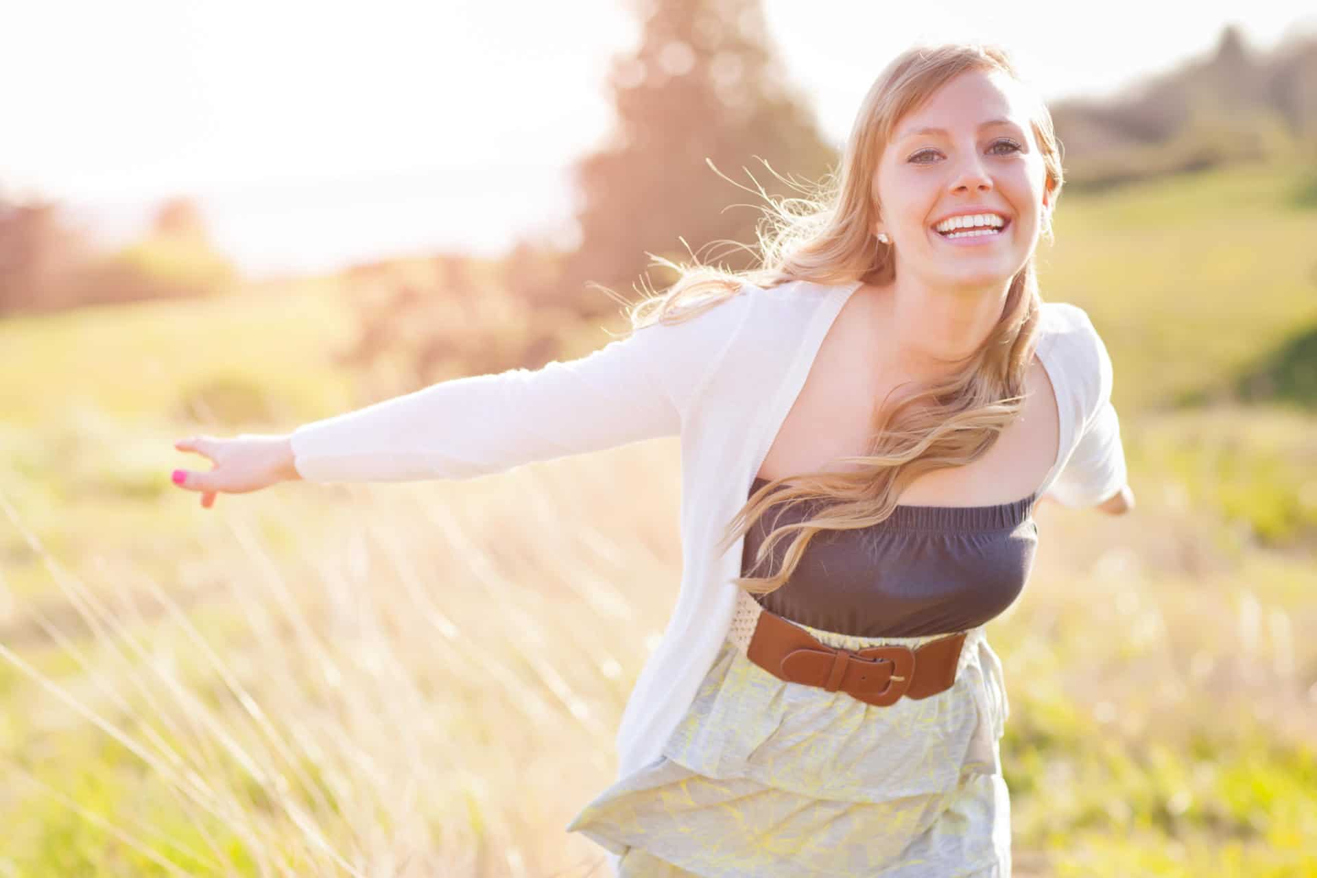Girl smiling and waving arms in field